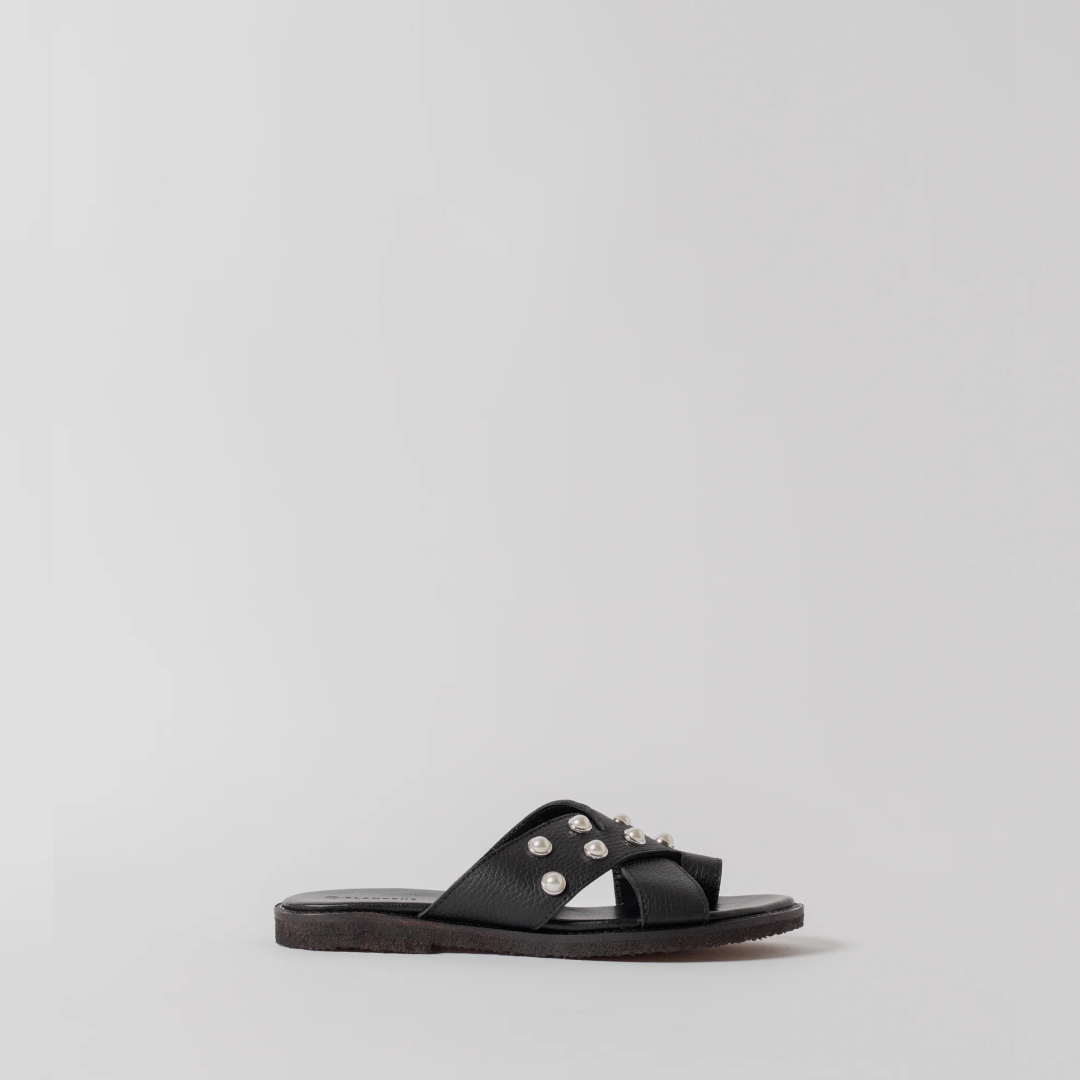 Black sandal with embellishments on a light gray background